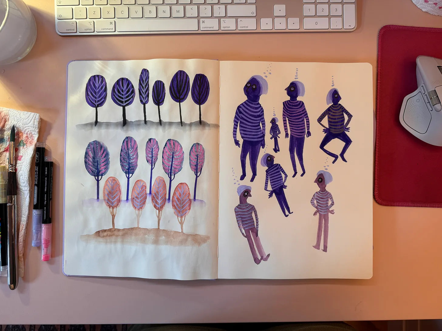 Open schetsboek met paarse bomen en figuren op een bureau.