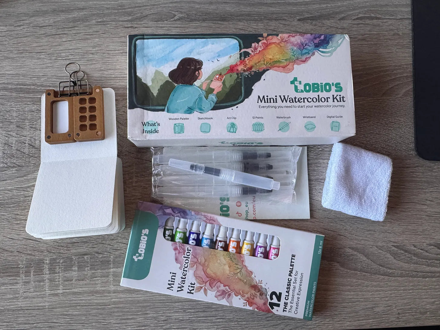 Miniatuurwaterverfset met verf, palet, penselen en papier.